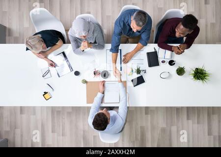 Gruppo di Corporate assunzione ufficiali agitando la mano con il candidato è arrivato per il colloquio Foto Stock