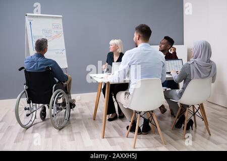 Disabili imprenditore maturo dando la presentazione ai suoi colleghi Foto Stock