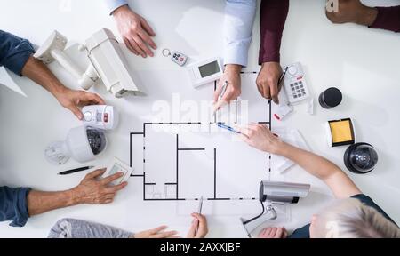 Il gruppo di tecnici di sicurezza lavorando sul Blueprint con le attrezzature di sicurezza sul tavolo Foto Stock