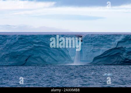 La ghiacciata di Nordaustlandet, con una cascata che si scioglie a causa dei cambiamenti climatici nell'arcipelago di Svalbard, Norvegia Foto Stock