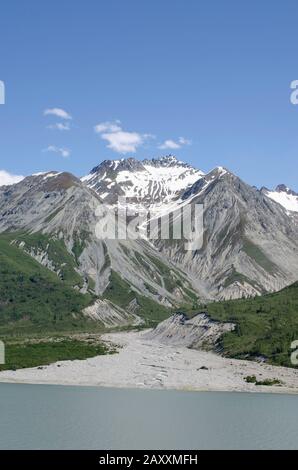 Glacier Bay circondato da aspre montagne riflesse nelle acque calme. Cielo limpido, cime di montagna innevata, con oceani di ghiacciaio e acque riflettenti. Foto Stock