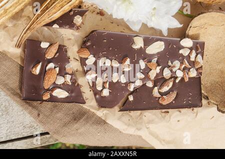 Cioccolato con dadi su legno rustico sfondo. Barra di cioccolato pezzi Foto Stock