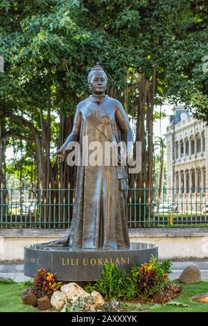 Honolulu Oahu, Hawaii, Stati Uniti. - 10 gennaio 2012: Statua bronzea della regina Liliuokalani con piante di fronte e albero Banyan sul retro. Foto Stock