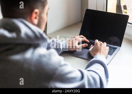 Vista posteriore di un giovane uomo che lavora con un notebook su un desktop Foto Stock