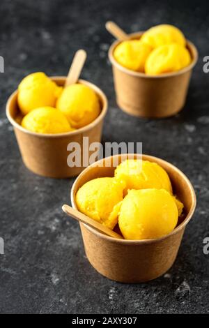 Scoop di gelato giallo in tazze di carta biologica Foto Stock