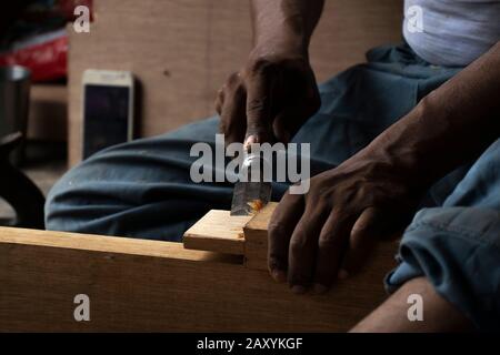 Falegname che lavora con sgorbia sul tavolo nella sua officina Foto Stock
