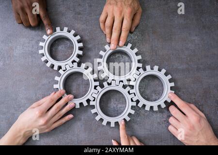 Un gruppo di imprenditori di unire insieme ingranaggi sul tavolo al posto di lavoro Foto Stock