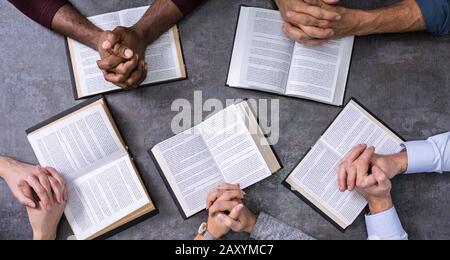 Vista in elevazione del popolo santo di lettura di libri su sfondo di legno Foto Stock