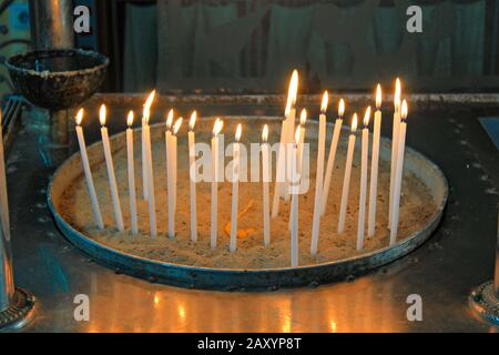 Candele di illuminazione all'interno di una chiesa greco ortodossa. Foto Stock