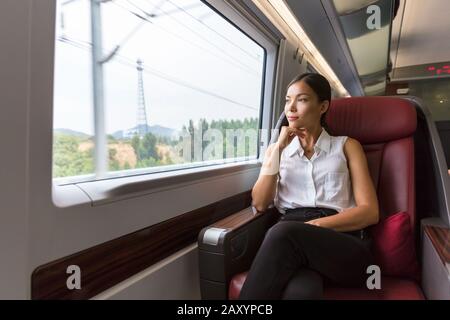 Donna che si rilassa godendosi la vista durante il viaggio di mattina. Posto a sedere in classe business in treno. Asian businesswoman pensive guardando fuori la finestra nel trasporto di viaggio. Foto Stock