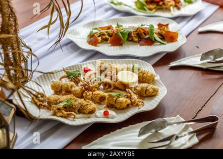 Calamari fritti e martoriati con salsa di catrame e limone serviti su un piatto bianco di ceramica. Foto Stock