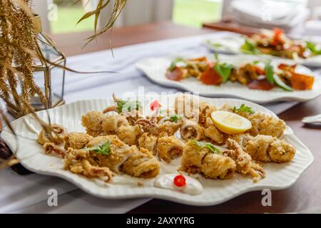 Calamari fritti e martoriati con salsa di catrame e limone serviti su un piatto bianco di ceramica. Foto Stock