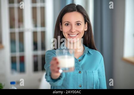 Giovane donna sorridente che beve latte nel morking Foto Stock