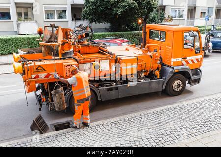 06 agosto 2019, Munchen, Germania: Il lavoratore del servizio di utilità della città elimina il deflusso delle fognature dalle acque meteoriche dall'intasamento. Foto Stock