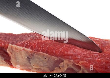 Il coltello da cucina taglia una bistecca cruda Foto Stock