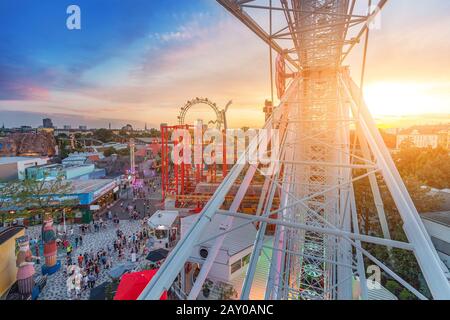Veduta aerea del parco divertimenti al tramonto con ruota ferris e montagne russe Foto Stock