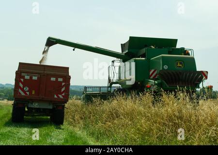 Trasferimento della granella da una mietitrebbia John Deere T670 Hillmaster a un rimorchio agricolo durante la raccolta del frumento nei pressi di Duras, Lot-et-Garonne, Francia. Foto Stock