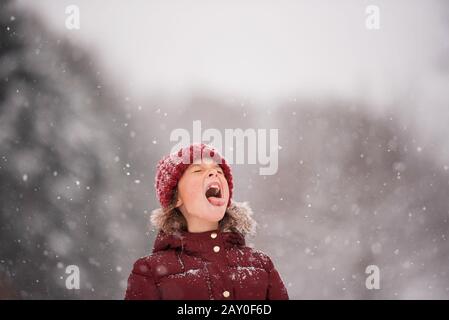 Ragazza in piedi all'aperto che cattura la neve in bocca, Wisconsin, Stati Uniti Foto Stock