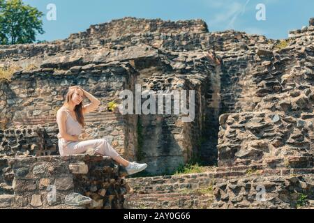 Ragazza turistica a piedi in antiche ruine romane o greche di anfiteatro antico Foto Stock