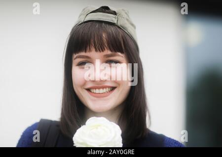 Ritratto di una donna sorridente in un cappellino da baseball con un fiore, Germania Foto Stock