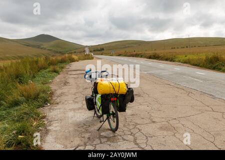 La bici da turismo si trova vicino alla strada asfaltata in Mongolia Foto Stock