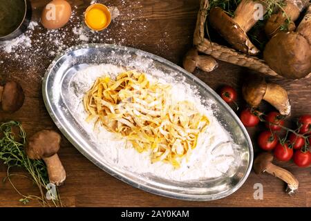 Tagliatelle appena preparate con funghi, pomodoro e timo Foto Stock