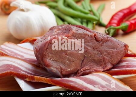 strisce di carne cruda e pancetta con verdure Foto Stock