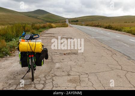 La bici da turismo si trova vicino alla strada asfaltata in Mongolia. Foto Stock