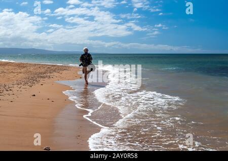 Ritratto di un uomo che cammina sulla spiaggia con macchina fotografica, Hawaii, Stati Uniti Foto Stock