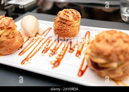 Delizioso dessert Profiteroles su un piatto del ristorante Foto Stock