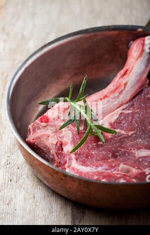 Bistecca T-Bone cruda in una padella di rame Foto Stock