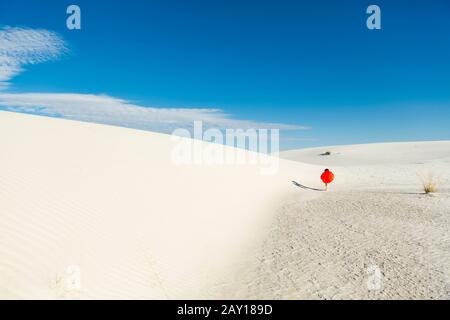 ragazzo di 6 anni che porta una slitta arancione in un paesaggio di dune ondulate bianco. Foto Stock