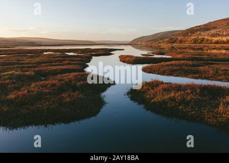 Estuario intertidale con canali d'acqua al tramonto Foto Stock