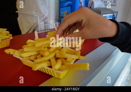 Oosterscheldekering, Paesi Bassi, Agosto 2019. La portata principale in un chiosco di cibo di strada: Patatine fritte. Una porzione è pronta per essere gustata, una mano è t Foto Stock