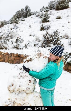 Ragazza teenage di tredici anni che costruisce un pupazzo di neve Foto Stock