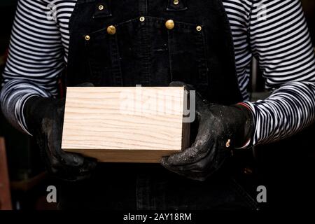 Primo piano di persone che indossano guanti di protezione con blocco di legno. Foto Stock