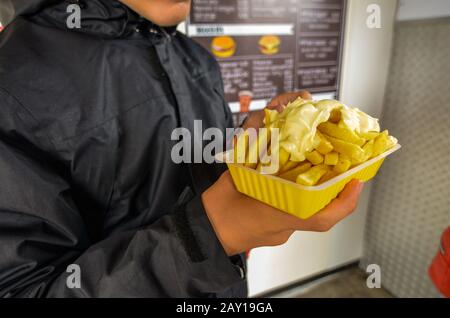 Oosterscheldekering, Paesi Bassi, Agosto 2019. La portata principale in un chiosco di cibo di strada: Patatine fritte. Una parte è tenuta in su con una mano mentre la th Foto Stock