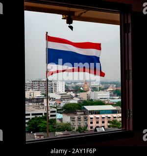 Bella vista da Wat Saket con bandiera Thai in primo piano e sullo sfondo i templi e gli edifici del centro di Bangkok, Thailandia Foto Stock