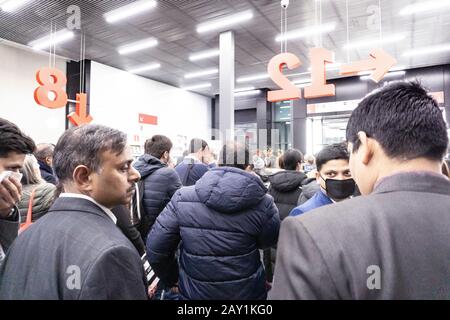 Folla di persone in coda per uscire da una fiera internazionale durante il coronavirus outburst, alcuni di loro indossando maschere per proteggere dal virus Foto Stock