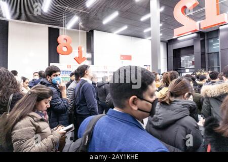 Folla di persone in coda per uscire da una fiera internazionale durante il coronavirus outburst, alcuni di loro indossando maschere per proteggere dal virus Foto Stock