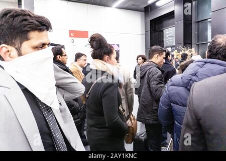 Folla di persone in coda per uscire da una fiera internazionale durante il coronavirus outburst, alcuni di loro indossando maschere per proteggere dal virus Foto Stock