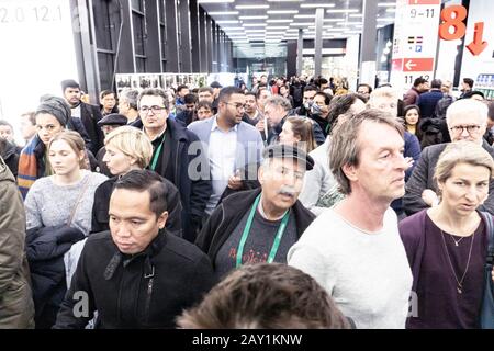 Folla di persone in coda per uscire da una fiera internazionale durante il coronavirus outburst, alcuni di loro indossando maschere per proteggere dal virus Foto Stock