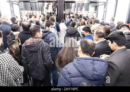 Folla di persone in coda per uscire da una fiera internazionale durante il coronavirus outburst, alcuni di loro indossando maschere per proteggere dal virus Foto Stock