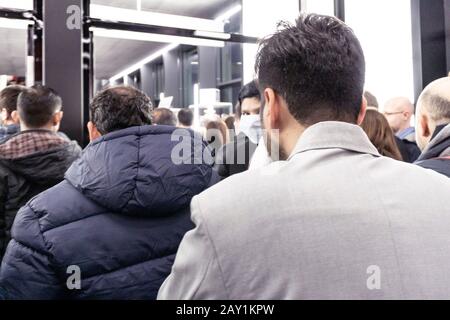 Folla di persone in coda per uscire da una fiera internazionale durante il coronavirus outburst, alcuni di loro indossando maschere per proteggere dal virus Foto Stock