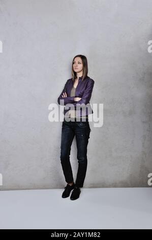 Bella giovane donna in piedi daydreaming e romanticizing le sue fantasie su sfondo grigio Foto Stock