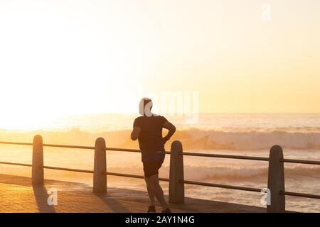 Jogger che corre sul mare al tramonto Foto Stock