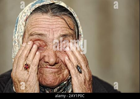 Donna matura che piange con le mani sul suo viso Foto Stock
