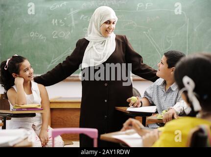 Insegnante di donne musulmane con bambini in classe nella scuola moderna Foto Stock
