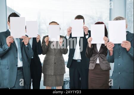 Team aziendale che tiene white paper in ufficio Foto Stock