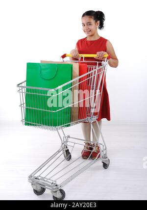 Piccola ragazza shopper in abito rosso con carrello Foto Stock